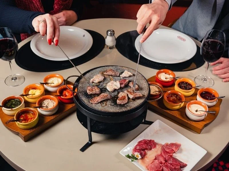 Carnes nobres grelhadas na pedra quente em restaurante de fondue de Gramado