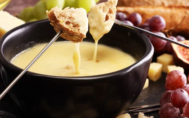 Panela de fondue de queijo derretido sendo servido em Gramado