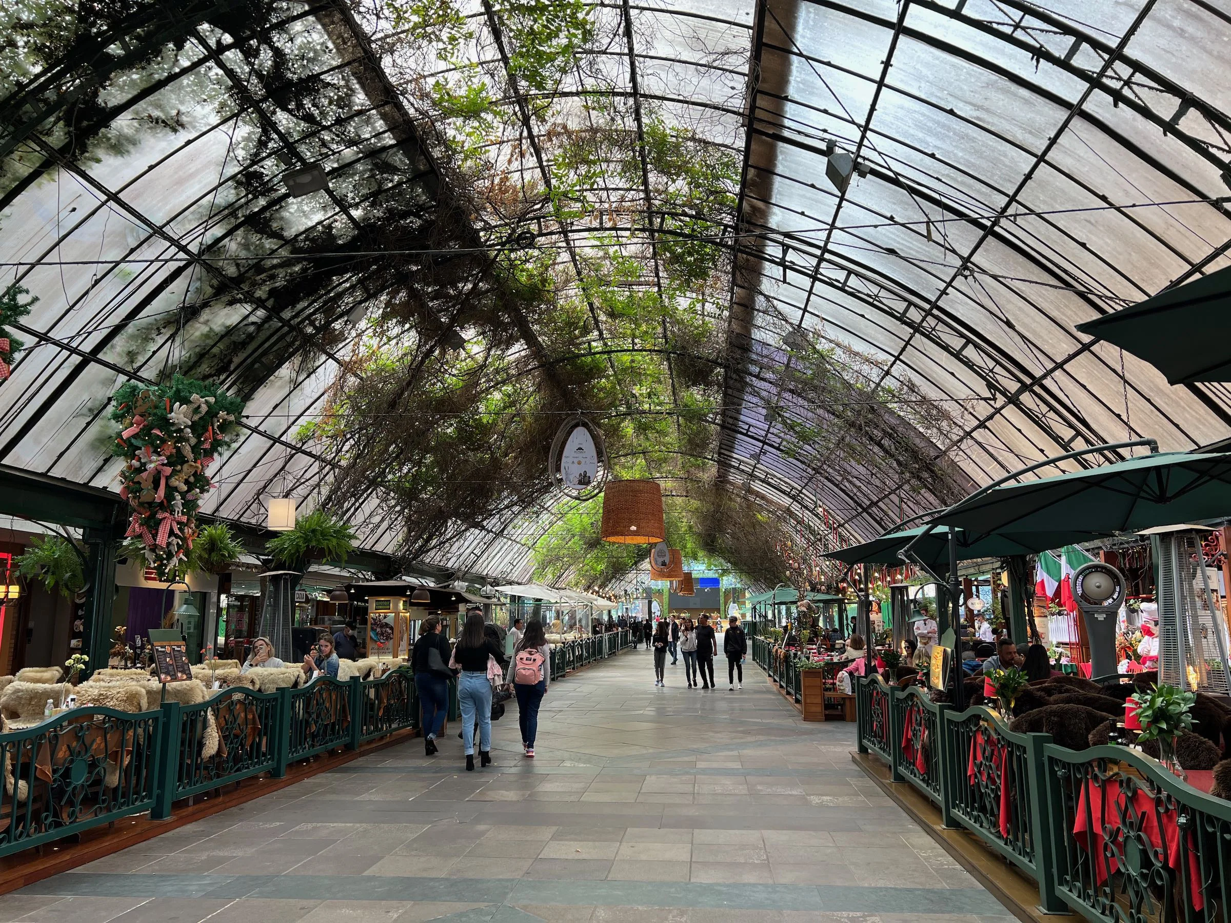 Rua Coberta de Gramado em dia de chuva com restaurantes e mesas